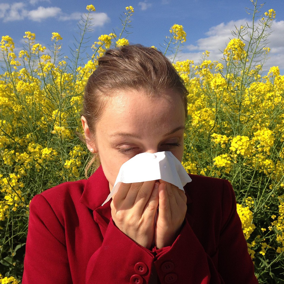 Une jeune femme allergique au milieu d'un champ de fleur