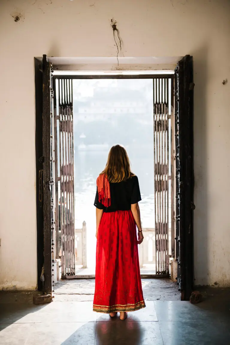 Femme face à une grille ouverte symbolisant un passage vers le changement, mais restant dans la zone de sécurité
