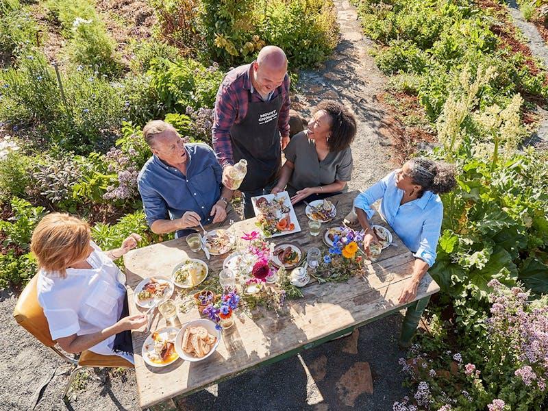 Personnes de tous horizons réunies autour d'une grande table en plein air.